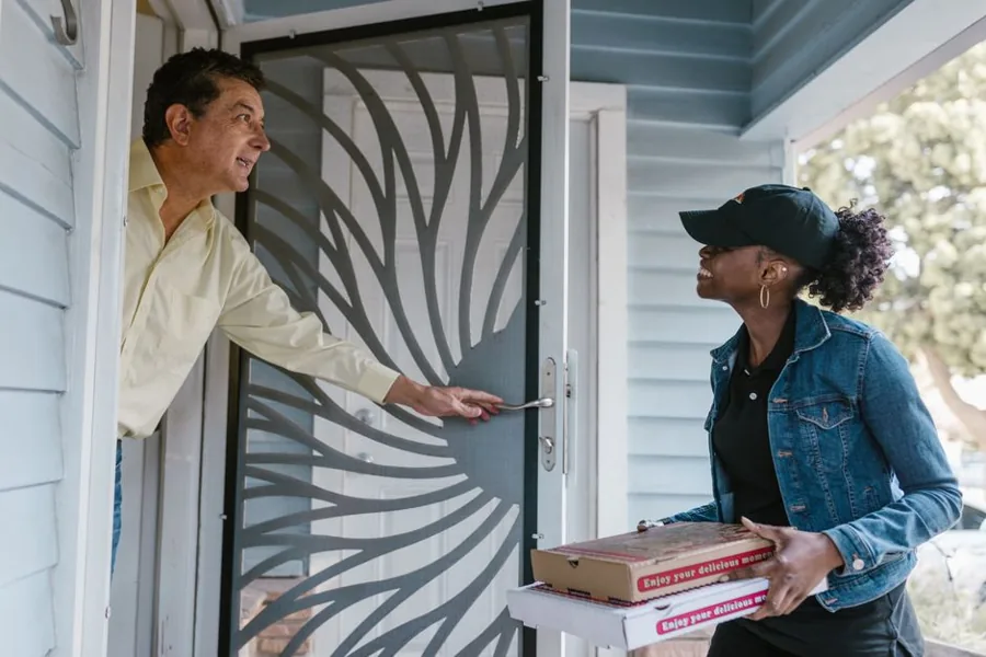 A home service technician greeting a satisfied customer at their front door after completing a job