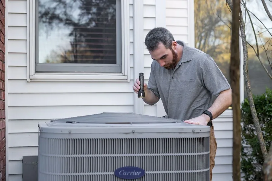 A uniformed home-service technician greeting a homeowner at the front door, tools in hand
