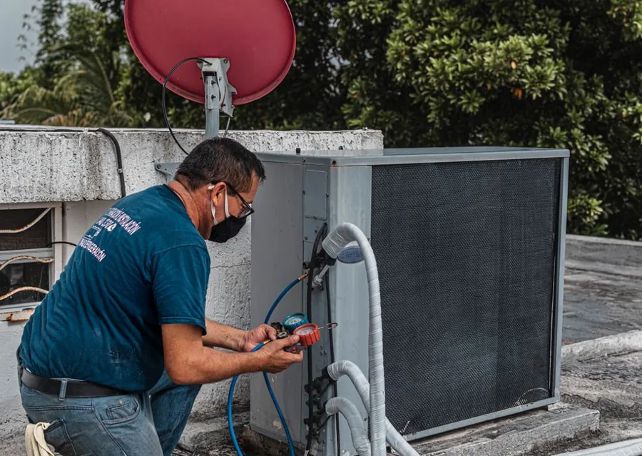 Home service technician servicing an outdoor air conditioning unit at a residential home