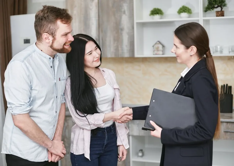 Uniformed home service technician shaking hands with a happy homeowner at her front door after finishing a job