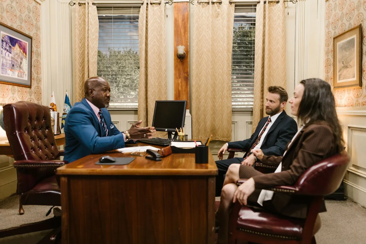 An attorney shaking hands with a prospective client across a desk in a law firm office