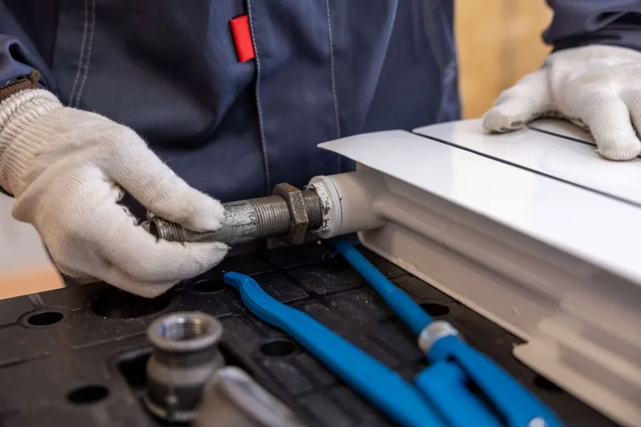 Plumber tightening a leaking pipe under a sink, a metaphor for fixing wasted ad spend